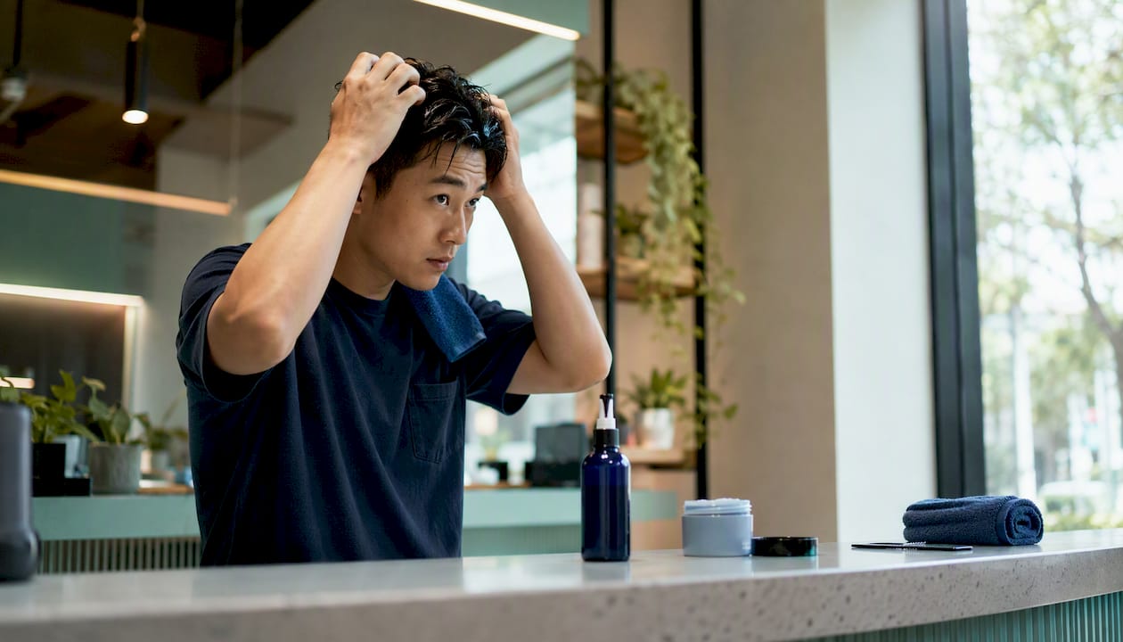 Asian man styling hair at vanity
