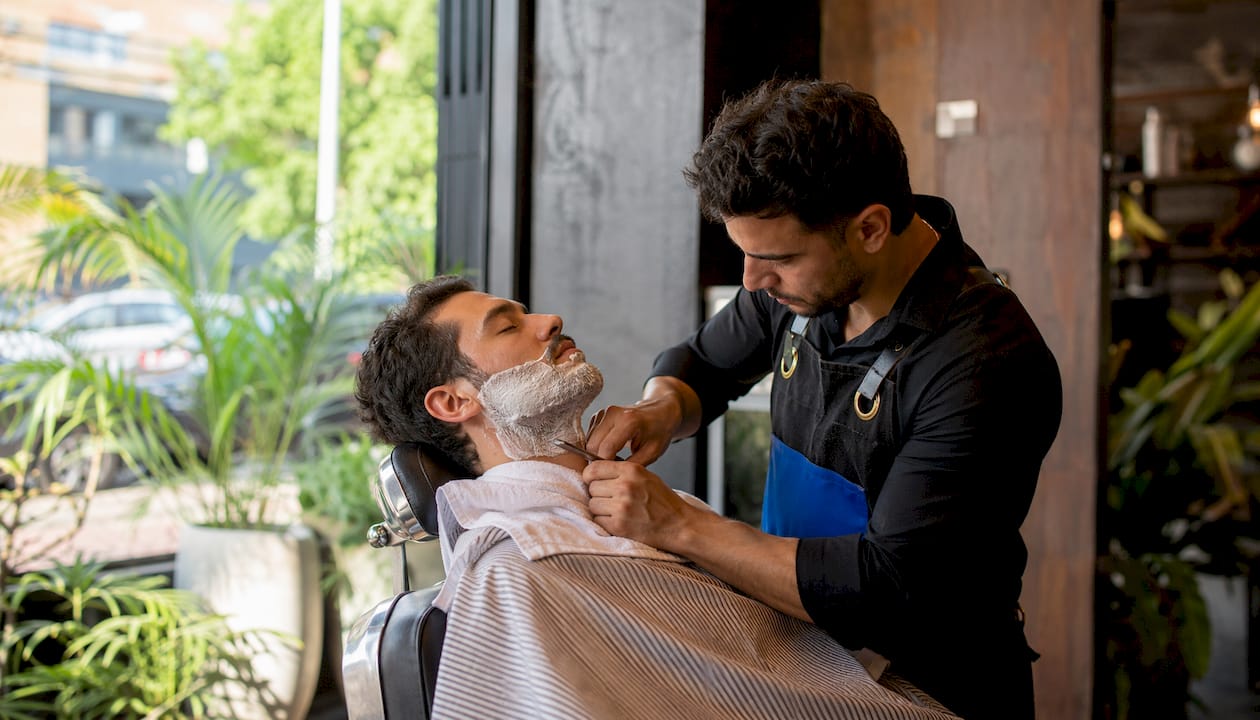 Barber giving straight-razor shave to male client